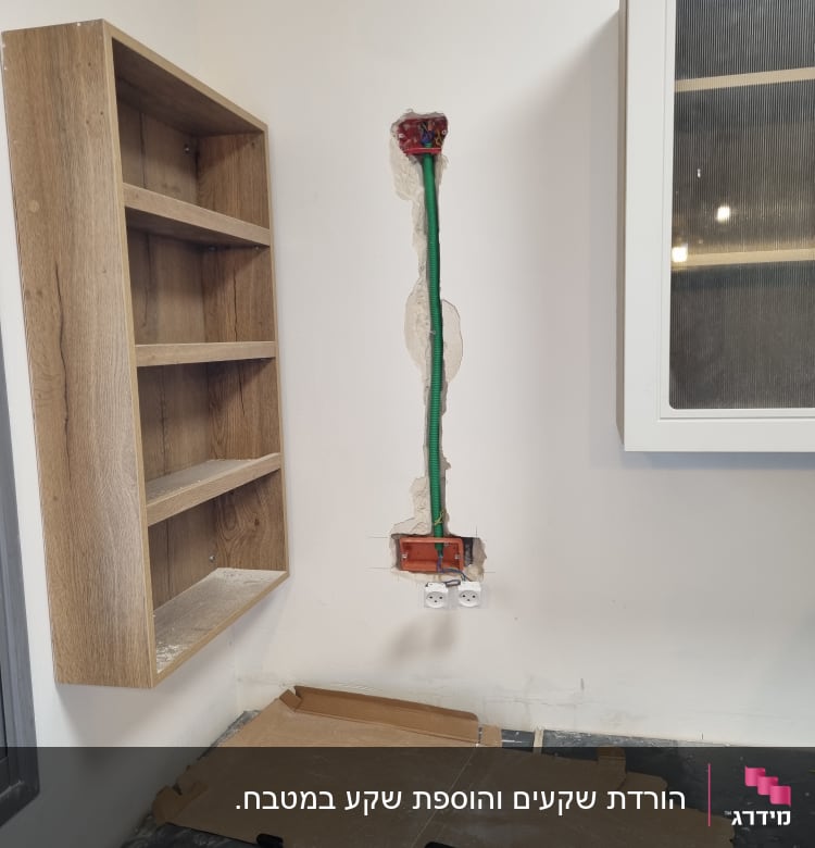 שקעי חשמל בקיר עם חוטים ירוקים וארון עץ